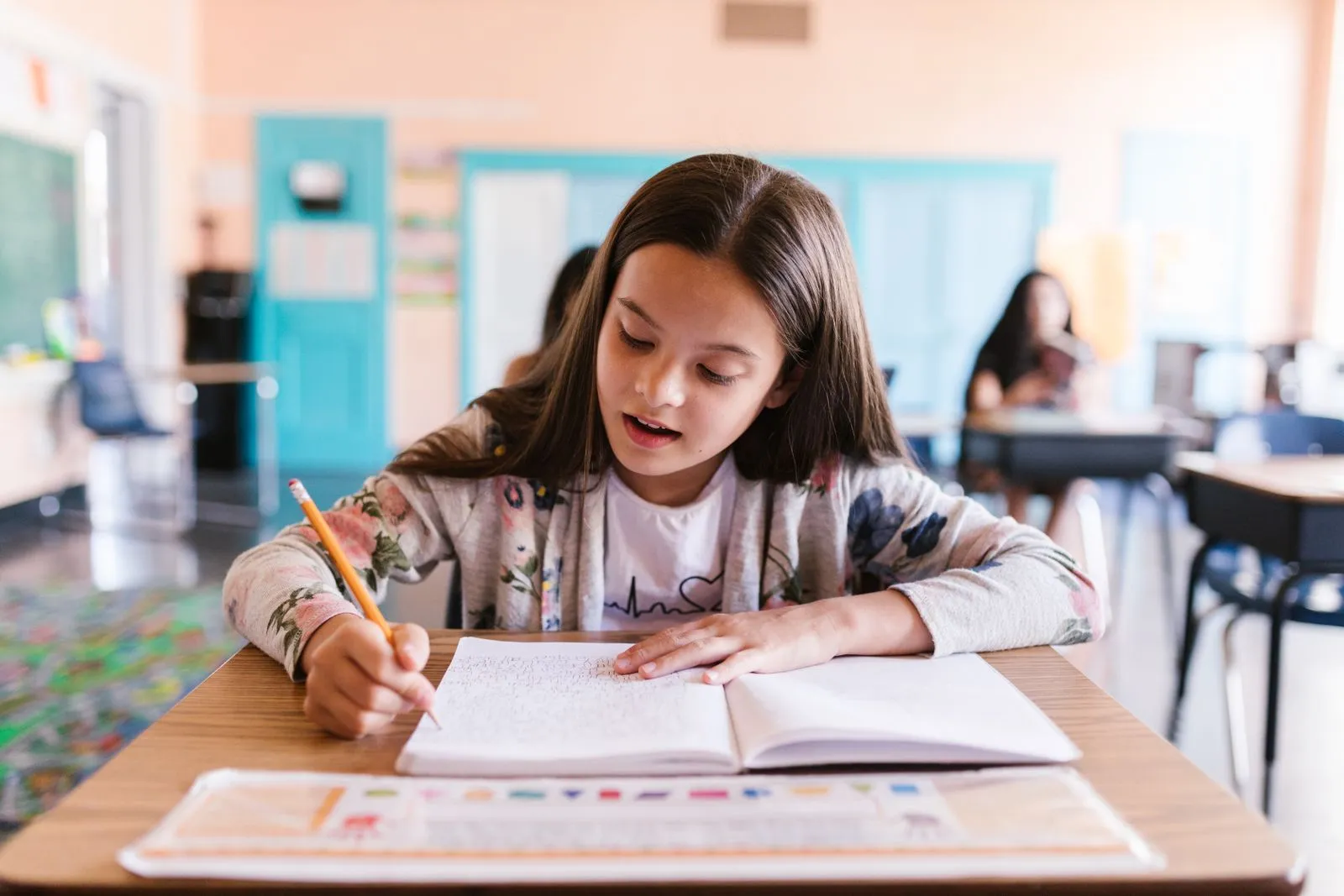 A young student writing carefully in her copybook at school