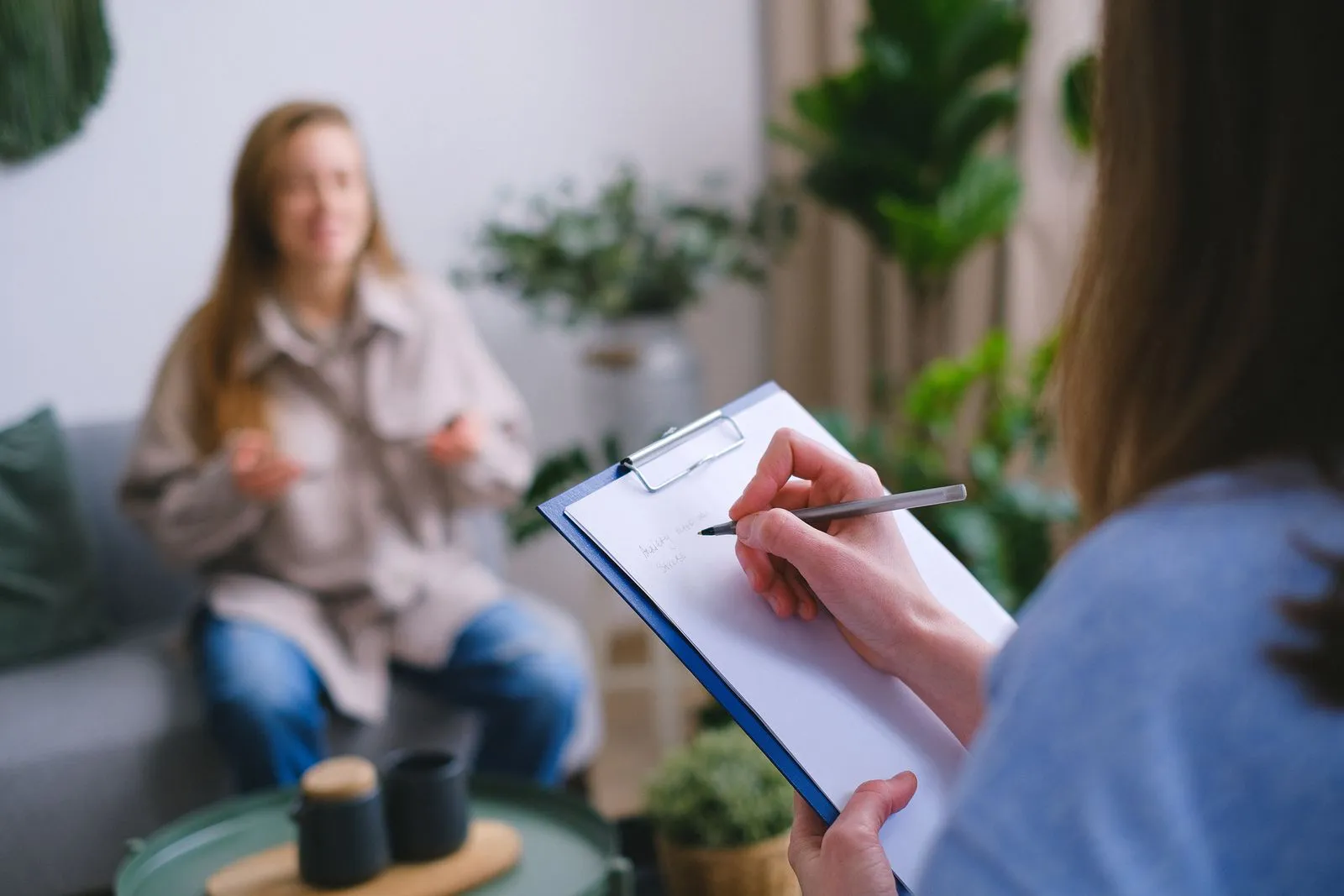 A psychologist taking notes during a calm one-to-one consultation